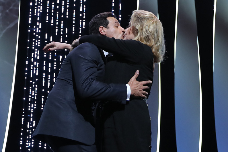 French actor and Master of Ceremony Laurent Lafitte (L) kisses French actress Catherine Deneuve on May 11, 2016 during the opening ceremony for the 69th Cannes Film Festival, southern France. / AFP PHOTO / Valery HACHE